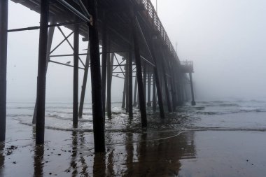 Oceanside Belediye İskelesi 'nin geniş açılı görüntüsü sabah sisinin altında, dalgalara ve kıyı şeridine karşı ahşap yapısını gözler önüne seriyor..