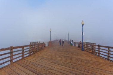 Okyanus Kenarı, Kaliforniya - 3 Ocak 2025: Kaliforniya 'daki Oceanside Belediye İskelesi manzarası, insanların okyanus kıyısındaki sisli atmosferin tadını çıkarmaları ve gezinmeleri.