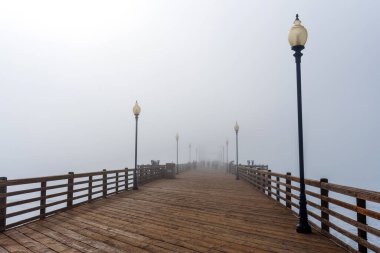 Oceanside, California - 3 Ocak 2025: Sisli bir sabahta Oceanside Belediye İskelesi 'nin geniş açılı görüntüsü, sis içinde kaybolan ahşap kalaslar ve lambalar sergiliyor..