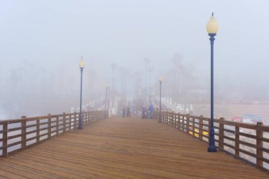 Oceanside, California - 3 Ocak 2025 Oceanside Pier 'in sisli sabah manzarası sisli bir şehir arkaplanı ile sakin atmosferi ve ahşap yapıyı yakalıyor..