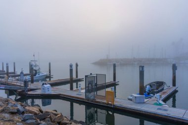 Oceanside, California - 3 Ocak 2025 Oceanside Limanı 'nda sakin, sisli bir sabah, durgun sular ve yumuşak sabah ışığı altında rıhtımda tekneler sergileniyor..