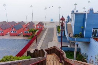 Oceanside, California - 3 Ocak 2025: Oceanside 'da palmiye ağaçları ve sisli plajlı canlı Roberts Kulübelerinin manzarası, sakin bir sahil atmosferi ve eşsiz bir mimariyi gözler önüne seriyor..