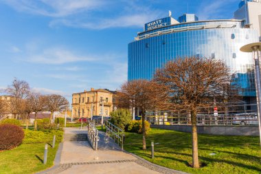 Kyiv, Ukrayna - 28 Mart 2025: Kyiv 'deki Hyatt Regency Oteli, parlak mavi gökyüzüne karşı modern cam cephe, manikürlü bahçeler ve patikalar.