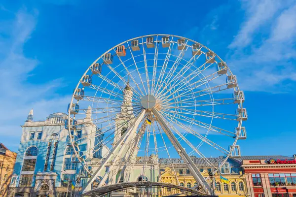 Kyiv, Ukrayna - 28 Mart 2025: Kyiv 'deki Kontraktova Meydanı' ndaki ikonik dönme dolabın geniş açılı görüntüsü, açık mavi gökyüzü ve canlı şehir manzarasına karşı yapısını gözler önüne seriyor.