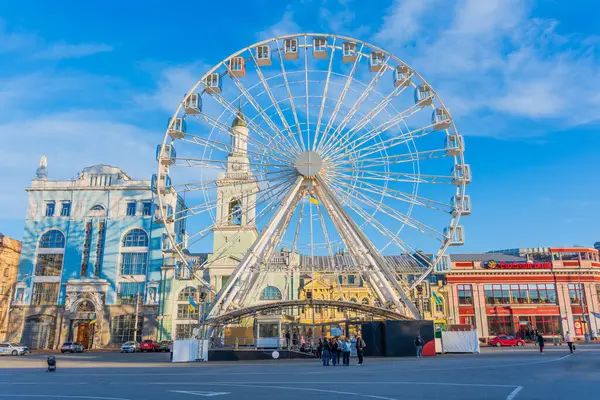 Kyiv, Ukrayna - 28 Mart 2025: Kyiv, Ukrayna 'daki Kontraktova Meydanı' nda parlak binalar ve açık mavi gökyüzü ile büyük dönme dolap.