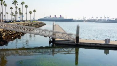 Long Beach, California - 11 Ocak 2025 Queen Mary 'nin ve etrafındaki Long Beach' in göz kamaştırıcı manzarası, canlı palmiye ağaçları ve dingin suları sergiliyor..