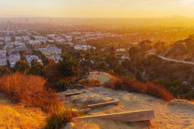 Gün batımında Runyon Canyon Parkı 'nda yürüyüş parkı boyunca bir gözlem noktasına giden adımların görüntüsü canlı renkleri ve kentsel manzarayı gözler önüne seriyor..