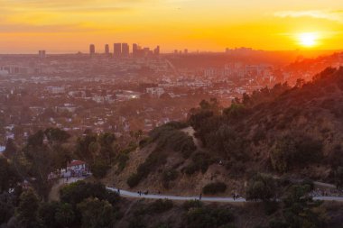 Los Angeles, California - 3 Aralık 2024 Runyon Canyon Parkı 'ndan büyüleyici panoramik günbatımı manzarası, Los Angeles ufuk çizgisini sergiliyor, sıcak altın renklerle yıkanmış, yürüyüşçülerin tadını çıkardığı.
