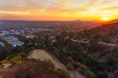 Los Angeles, Kaliforniya - 3 Aralık 2024 Los Angeles Runyon Canyon Parkı 'ndan nefes kesici gün batımı manzarası, gökyüzünde canlı renkler ve aşağıdaki şehir manzarasının panoramik bir görüntüsü.