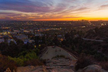 Los Angeles, California - 3 Aralık 2024: Runyon Canyon Park 'taki manzaralı manzaradan Los Angeles üzerinde gün batımına hayran olan bir grup yürüyüşçü.