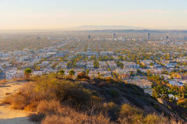 Los Angeles, Kaliforniya - 6 Ocak 2025: Runyon Canyon Park 'ın tepesinden Los Angeles' ın geniş manzarası, canlı şehir yaşamını ve günbatımında doğal manzarayı gözler önüne seriyor.