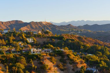 Los Angeles, California - 6 Ocak 2025 Hollywood tabelasının altındaki prestijli yerleşim bölgesi altın akşam ışığı, lüks gayrimenkul konseptiyle güneşleniyor.