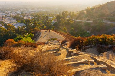 Los Angeles, Kaliforniya - 28 Kasım 2024: Yürüyüşlerin Los Angeles 'ın akşam parıltısını izlemek için durduğu gün batımına giden adımlar.