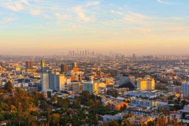 Los Angeles, Kaliforniya - 3 Aralık 2024: Güneşin batışında ufuk çizgisini sergiliyor, şehrin ikonik binalarını sıcak altın renkleri ve açık gökyüzüyle vurguluyor.