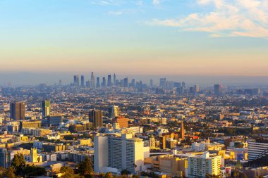 Los Angeles, Kaliforniya - 3 Aralık 2024: Gün batımında Los Angeles 'ın panoramik manzarası, gökdelenler, şehir manzaraları ve sahneyi aydınlatan yumuşak altın renkli canlı şehir ışıkları.
