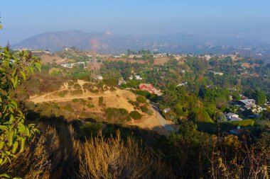 Los Angeles, Kaliforniya - 5 Aralık 2024: Los Angeles 'ın geniş tepeleri, gündüz gözüyle görülen ikonik Hollywood tabelasıyla lüks evleri sergiliyor.