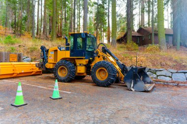 Sequoia Ulusal Parkı, Kaliforniya - 30 Kasım 2024: Sequoia Ulusal Parkı 'ndaki çakıllı yolda park etmiş kedi ağır ekipman yükleyicisi, yüksek sekoya ağaçları ve sonbahar yapraklarıyla çevrili.