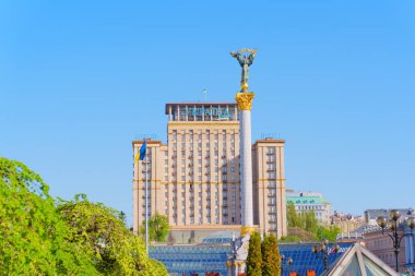 Kyiv, Ukrayna - 22 Nisan 2025: Açık mavi gökyüzüne karşı kentsel mimari sergilenen Independence Anıtı ve Otel Ukrayna ile Meydan Nezalezhnosti 'nin parlak gündüz görünümü.
