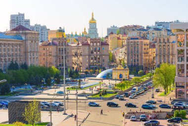 Kyiv, Ukrayna - 22 Nisan 2025: Güneşli bir bahar gününde Meydan Nezalezhnosti 'de hareketli bir sahne, tarihi binalar, yeşil alanlar ve canlı şehir hayatı sergileniyor.