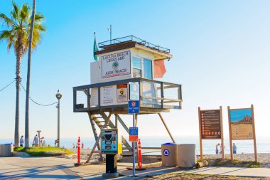 Long Beach, California - 8 Aralık 2024 Long Beach, Kaliforniya 'da Aliso Sahili manzaralı cankurtaran kulesi, açık mavi gökyüzü ve ön planda palmiye ağaçları ile gün ışığında yakalandı..