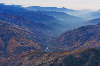 Sequoia Ulusal Parkı 'nın alacakaranlıktaki geniş açılı manzarası katmanlı dağları, vadileri ve ufku kaplayan yumuşak bir sisi gösteriyor..