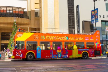 Los Angeles, Kaliforniya - 23 Aralık 2024 Los Angeles 'ta bir şehir caddesine park etmiş canlı, açık manzaralı bir otobüs festival atmosferinde parlak renkler ve turistik gösteriler sergiliyor..