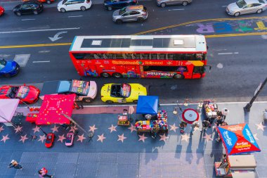 Los Angeles, Kaliforniya - 23 Aralık 2024: Hollywood Bulvarı 'nın canlı hava görüntüsü, Los Angeles' ta kırmızı bir tur otobüsü, renkli bayi tezgahları ve yoğun trafiği gösteriyor.