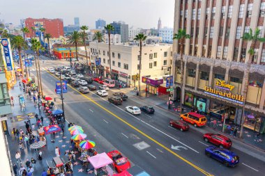 Los Angeles, Kaliforniya - 23 Aralık 2024: Hollywood, Los Angeles 'ta hareketli sokak manzarası, hareketli trafik, renkli şemsiyeler ve parlak gün ışığı altında ikonik dükkanlar.