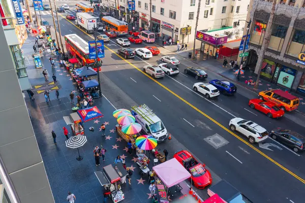 Los Angeles, Kaliforniya - 23 Aralık 2024: Trafikle, satıcılarla ve renkli şemsiyelerle hareketli bir Hollywood caddesinin hareketli manzarası, Los Angeles 'ın canlı atmosferini gözler önüne seriyor.