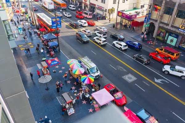 Los Angeles, Kaliforniya - 23 Aralık 2024: Los Angeles Hollywood Bulvarı 'nın hareketli manzarası, canlı sokak satıcıları, kaldırımda ikonik yıldızlar ve arabalarla dolu kalabalık bir cadde.