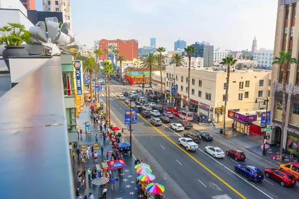 Los Angeles, Kaliforniya - 23 Aralık 2024 Los Angeles, Kaliforniya 'da hareketli sokak manzarası, parlak mavi gökyüzü altında renkli şemsiyeler, yoğun trafik ve palmiye ağaçları sergileniyor.