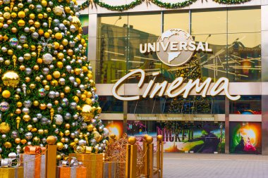 Los Angeles, Kaliforniya - 24 Aralık 2024: Los Angeles Universal Cinema 'nın dışında altın ve yeşil süslemelerle süslenmiş büyük bir Noel ağacını gösteren festival sahnesi.