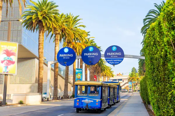 Los Angeles, California - 24 Aralık 2024: Vibrant Universal Stüdyoları Los Angeles 'ta palmiye çizgili bir cadde boyunca seyahat eden ziyaretçiler.