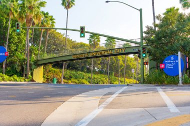 Los Angeles, Kaliforniya - 24 Aralık 2024: Universal City, Los Angeles 'ta gün ışığında trafik ışıkları ve palmiye ağaçlarını gösteren ikonik hoş geldin tabelasına bakın.