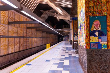 Los Angeles, California - 23 Aralık 2024: Evrensel Şehir Metro Tren İstasyonu 'nun geniş açılı görüntüsü canlı duvar resimleri ve fayanslı duvarlar, boş platformlar ve tepeden aydınlatma.
