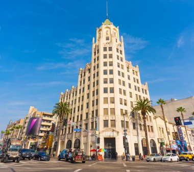 Los Angeles, Kaliforniya - 23 Aralık 2024: Iconic Hollywood First National Building Los Angeles 'ta açık mavi gökyüzünün altında, palmiye ağaçları ve hareketli sokaklarla çevrili.