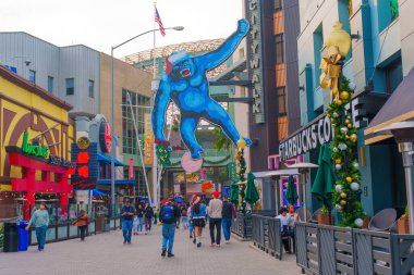 Los Angeles, Kaliforniya - 24 Aralık 2024: Los Angeles Universal CityWalk 'da geniş mavi goril heykeli ve hareketli yayaların yer aldığı canlı sokak sahnesi.