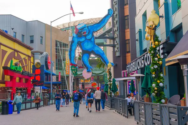 Los Angeles, Kaliforniya - 24 Aralık 2024: Los Angeles Universal CityWalk 'da geniş mavi goril heykeli ve hareketli yayaların yer aldığı canlı sokak sahnesi.