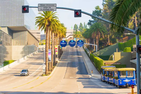 Los Angeles, California - 23 Aralık 2024: Universal Stüdyoları Hollywood 'daki tramvay geçidi tabelasının görüntüsü, palmiye ağaçları, açık gökyüzü ve yakınlarda park edilmiş klasik bir tramvay.