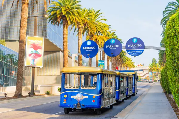 Los Angeles, Kaliforniya - 24 Aralık 2024: Universal Stüdyoları 'ndan tramvay Los Angeles' ta bir park levhasının altında yol alıyor..