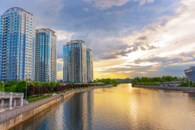 Kyiv, Ukrayna - 19 Mayıs 2025: Günbatımında Dinyeper Nehri 'nin yanındaki Riverstone konut kompleksinin görüntüsü, modern mimari ve dingin su yansımaları sergilenmektedir..