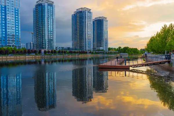 Kyiv, Ukrayna - 19 Mayıs 2025: Ukrayna 'nın başkenti Kyiv' de günbatımında sakin bir nehre yansıyan modern yerleşim binalarının geniş açılı görüntüsü.