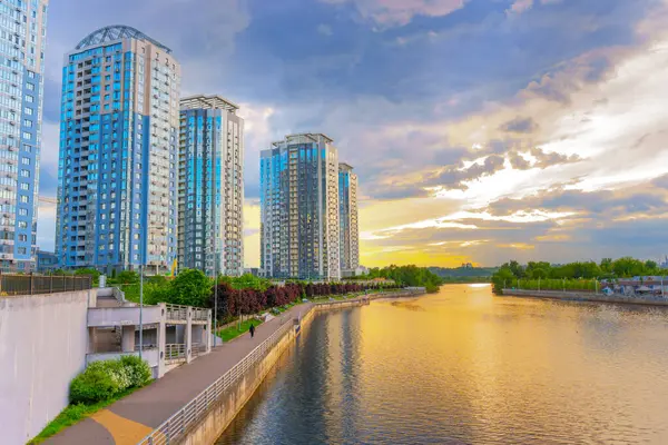 Kyiv, Ukrayna - 19 Mayıs 2025: Kyiv, Ukrayna 'daki Riverstone konut kompleksinin panoramik manzarası, günbatımında sakin bir nehrin yanında modern yüksek binaların yer aldığı.