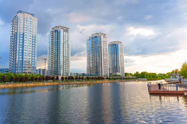 Kyiv, Ukrayna - 19 Mayıs 2025: Kyiv 'deki Riverstone konut kompleksi günbatımında sakin sulara yansıyan yüksek binalar.