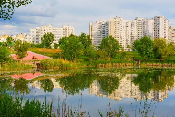 Kyiv, Ukrayna - 19 Mayıs 2025: Poznyaky Gölü 'nün sakin manzarası Kyiv' deki konut binalarını ve yemyeşil alanları yansıtıyor..