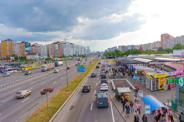 Kyiv, Ukrayna - 19 Mayıs 2025: Kyiv 'deki Bazhana Caddesi' nin geniş açılı görüntüsü trafik, binalar ve Poznyaky Metro İstasyonu yakınlarında bulutlu gökyüzünün altında hareketli bir sokak pazarı.