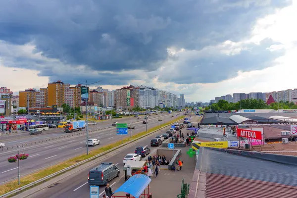 Kyiv, Ukrayna - 19 Mayıs 2025: Bulutlu bir gökyüzü altında yayalar, araçlar ve şehir mimarisini gösteren Kyiv 'deki Poznyaky Metro istasyonu yakınlarındaki işlek sokak manzarası.