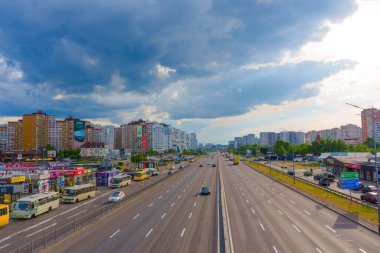 Kyiv, Ukrayna - 19 Mayıs 2025: Ukrayna 'nın Kyiv kentindeki işlek bir otoyolun gün boyunca kentsel binalar ve bulutlu gökyüzü manzarası.