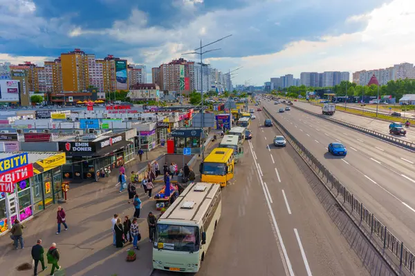 Kyiv, Ukrayna - 19 Mayıs 2025: Kyiv 'deki Poznyaky Metro İstasyonu' nda park etmiş çeşitli otobüslerin görüntüsü, kentsel binalar ve çevresindeki insanlarla birlikte.