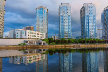 Kyiv, Ukrayna - 19 Mayıs 2025: Kyiv 'deki River Mall rıhtımının geniş açılı çekimi, modern binaların yansımalarını ve sudaki yakın bir okulun yansımalarını sergiliyor.